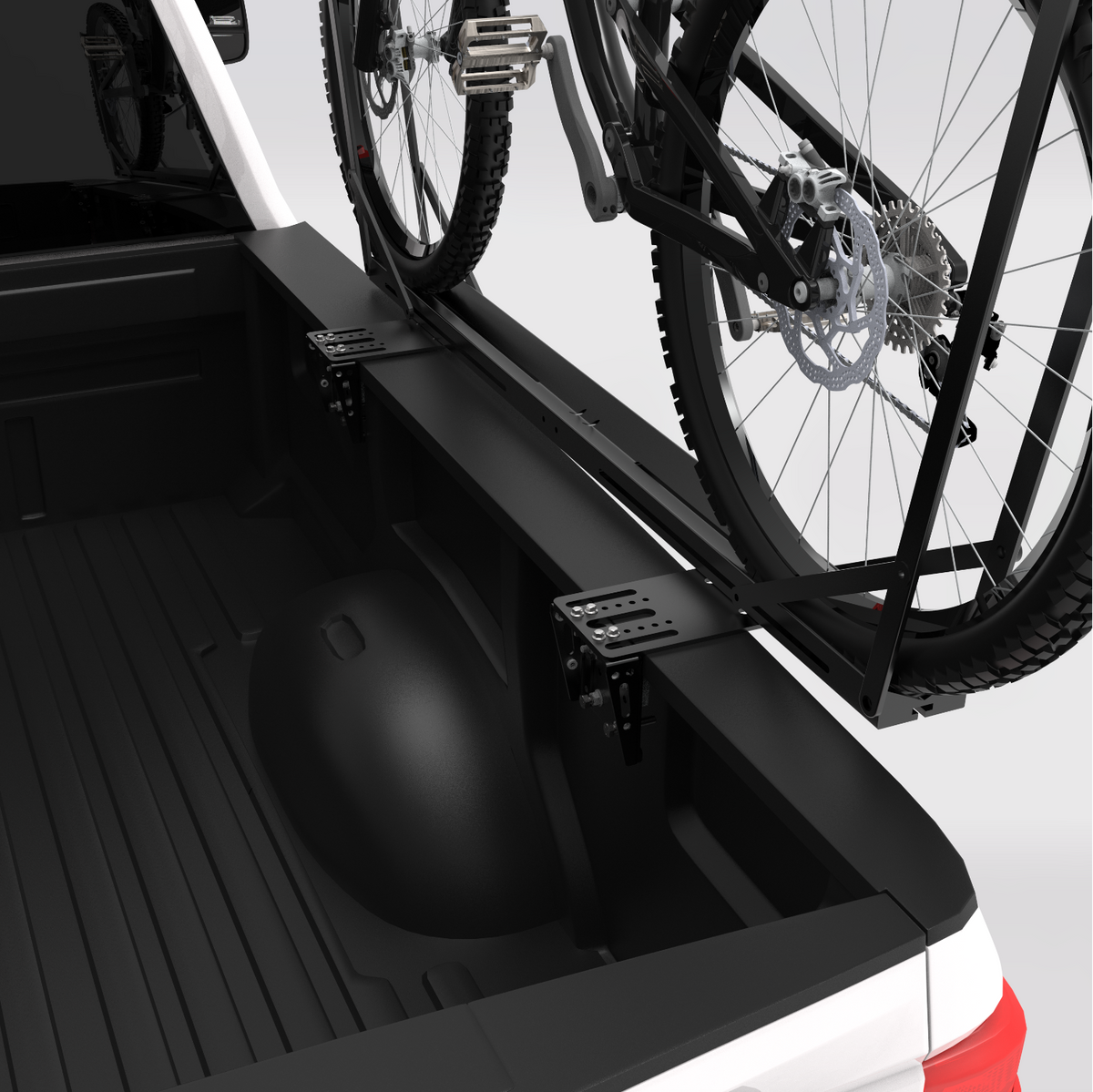 A black bicycle rack mounted on the bed of a white pickup truck, holding a black bicycle. The rack is shown from a high angle inside the truck bed. STAPLL side mount bike rack.